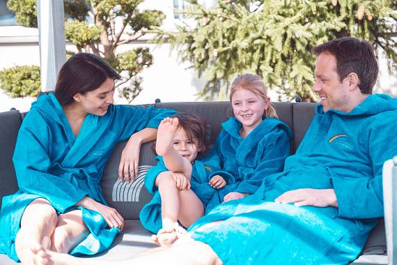 Familie im Bademantel genie&szlig;t den Wellnessurlaub
