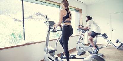 Wellnessurlaub - Ganzkörpermassage - Flachau - Fitnessraum mit TOP Geräten und Ausblick - Design & Wellness Hotel Alpenhof