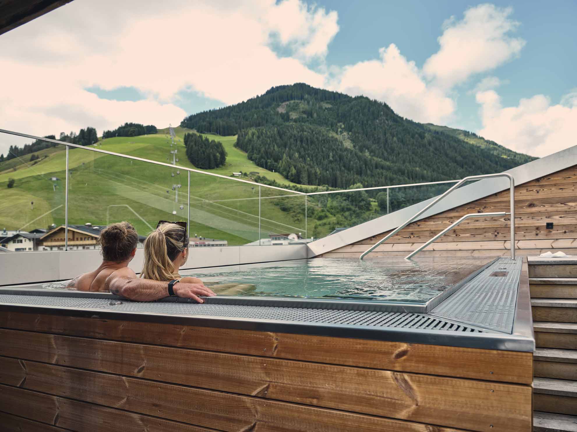 Wellnesshotel - Paar im Außenpool mit Blick auf die Berge - Hotel Hasenauer