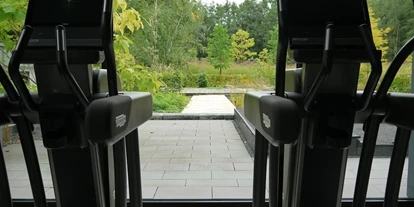 Wellnessurlaub - Gelsenkirchen - Blick aus der Fitnesshalle in den Garten mit Schwimmteich - Essensio Hotel