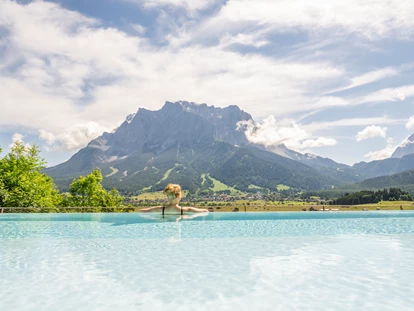 Wellnessurlaub - Fahrradverleih - Innsbruck - Dame im Pool mit Zugspitzblick - Hotel Post Lermoos