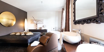 Wellnessurlaub - Restaurant - Stegersbach - Grand Fantasy Suite Die Grand Fantasy Suite sorgt mit ihren 80m² für prickelnde Momente zu zweit. Die Basis hierfür bietet ein extragroßes „Seally“ Deluxe Bett. Das „Open-Space“ Badezimmer besitzt eine große Dusche, einen Fön und ein separates WC mit Bidet. Die freistehende Badewanne dient als echte - Maiers Kuschelhotel Loipersdorf Deluxe