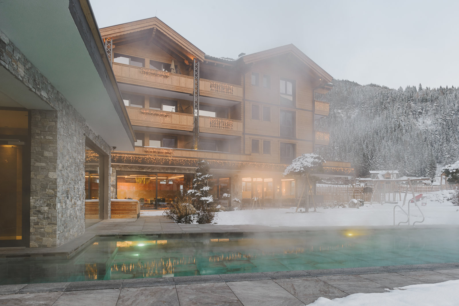 Wellnesshotel: Winterauszeit im Acherl: Im beheizten Außenpool entspannen und den Blick auf das Hotel und die verschneite Berglandschaft genießen. - Boutiquehotel Acherl