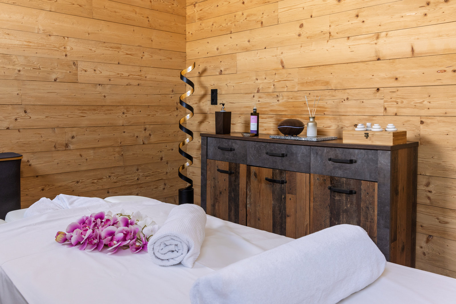 Wellnesshotel: Kleine Details zum Wohlfühlen: Liebevoll arrangierte Handtücher und Blüten auf dem Bett treffen auf warme Holzelemente im Acherl. - Boutiquehotel Acherl