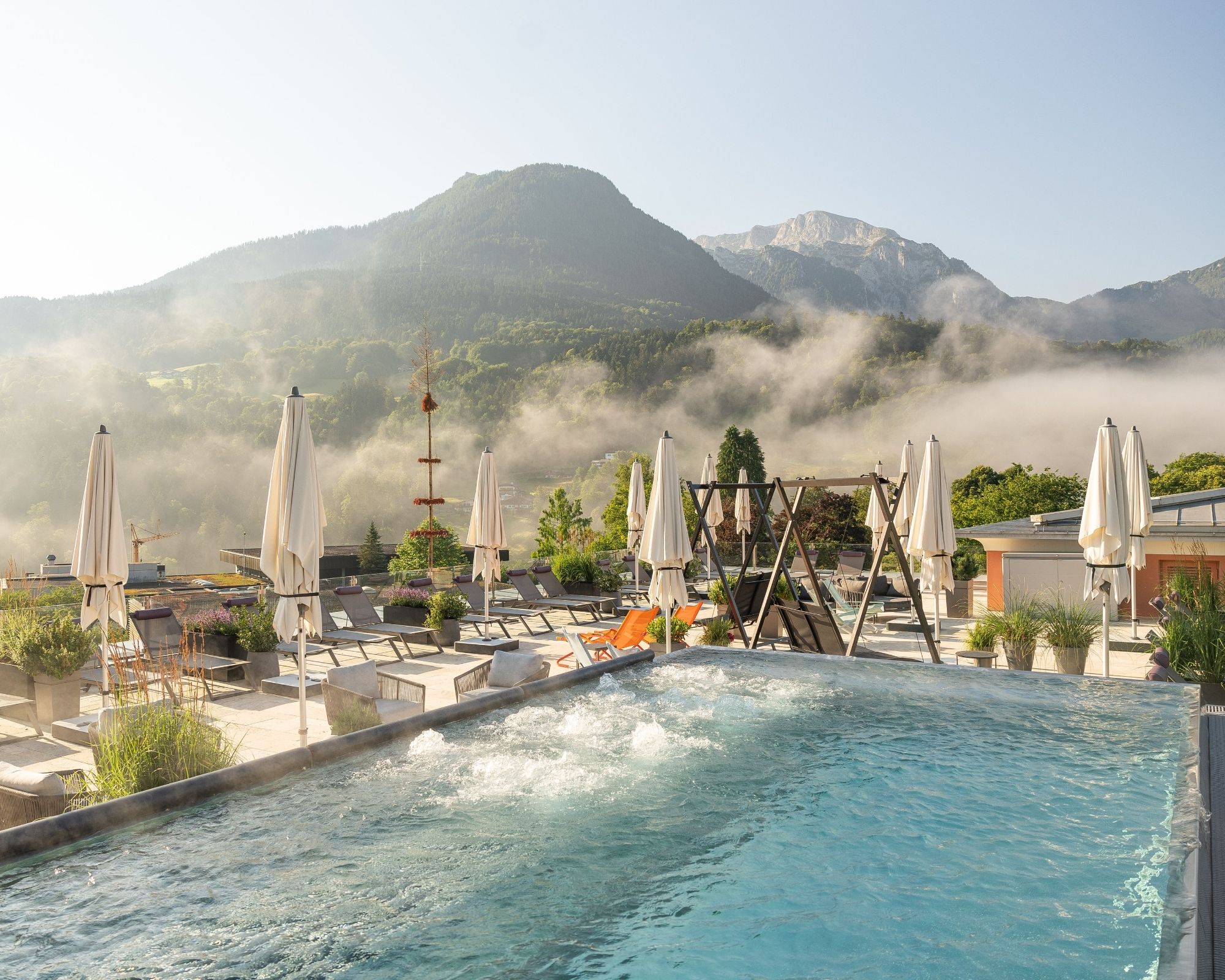 Wellnessurlaub - Lomi Lomi Nui - Dachterrasse mit Infinity Whirlpool, Liegen und Bergpanorama am Morgen - Hotel EDELWEISS Berchtesgaden