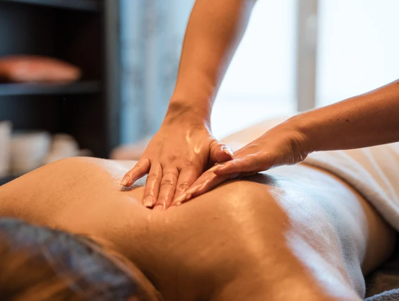 Wellnesshotel: Eine Frau genießt eine entspannende Rückenmassage im Wellnessbereich des Posthotels Rattenberg. - Posthotel Rattenberg - Sauna | Spa