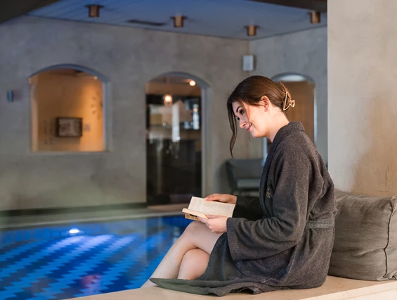 Wellnesshotel: Eine junge Frau liest ein Buch am Rand vom Schwimmbad - Posthotel Rattenberg - Sauna | Spa