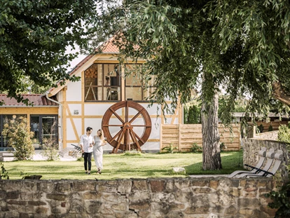 Wellnessurlaub - Maniküre/Pediküre - Flomborn - SPA Garten mit Blick auf das alte Mühlrad und den Panorama Yoga Raum - Hotel Jordan's Untermühle