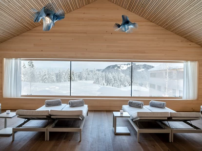 Wellnessurlaub - Fontanella - Relax-Raum: Hier lässt es sich wunderbar lesen, über das Leben sinnieren oder auch einfach nur relaxen. Der holzgetäfelte Giebel entschleunigt mit räumlicher Entspanntheit. Das heimische Holz mit seiner feinen Maserung ziert den schönen Raum wie ein Gemälde. Oder sie schicken Ihre Gedanken durch das große Blickfenster in die Natur auf Reisen.  - Fuchsegg Eco Lodge
