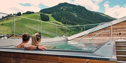 Wellnessurlaub - Pilates - Paar im Außenpool mit Blick auf die Berge - Hotel Hasenauer