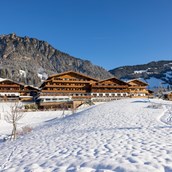 Wellnesshotel - Winterliche Südansicht des Hotels mit Bergen im Hintergrund - Der Alpbacherhof ****s Natur & Spa Resort