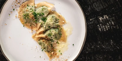 Wellnessurlaub - Dorf Tirol - Traditionelle Schlutzkrapfen – Mit Roggenmehl, einer delikaten Spinat-Quark-Füllung, verfeinert mit Nussbutter und Parmesan. Ein wahres Meisterwerk der Südtiroler Küche. - Alpin Garden Luxury Maison & SPA