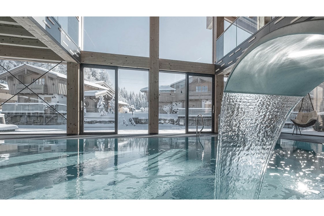 Wellnesshotel: INNs HOLZ Ausblick vom Indoorpool auf das Chaletdorf im Winter - INNs HOLZ Chaletdorf