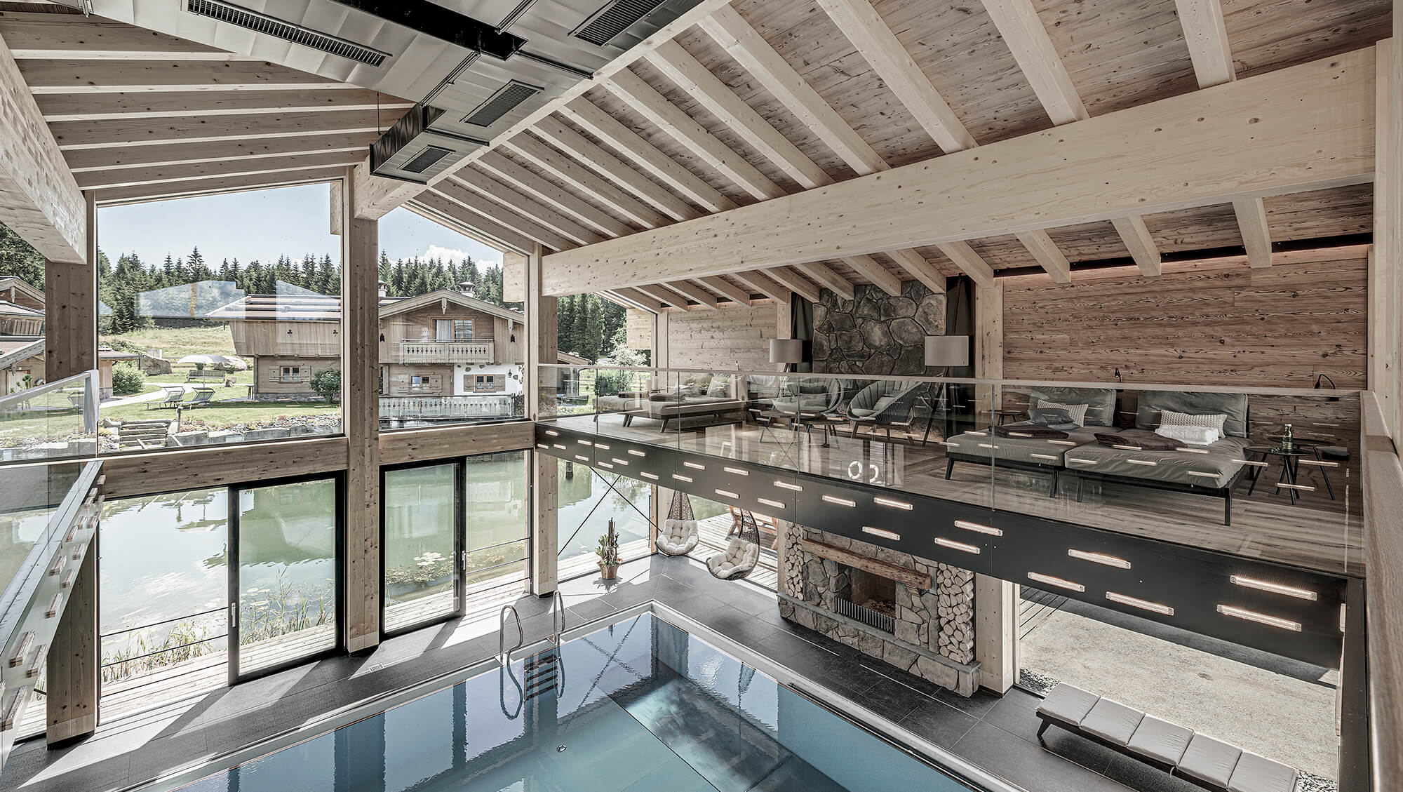Wellnesshotel: INNs HOLZ Chaletdorf Waldblick-Panoramalounge mit Blick auf Indoorpool, INNs HOLZ See und Chaletdorf im Sommer - INNs HOLZ Chaletdorf - Wasser, Zimmer | Suiten