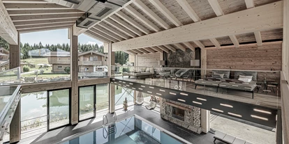 Wellnessurlaub - Private Spa - Otterbach (Sankt Florian am Inn) - INNs HOLZ Chaletdorf Waldblick-Panoramalounge mit Blick auf Indoorpool, INNs HOLZ See und Chaletdorf im Sommer - INNs HOLZ Chaletdorf