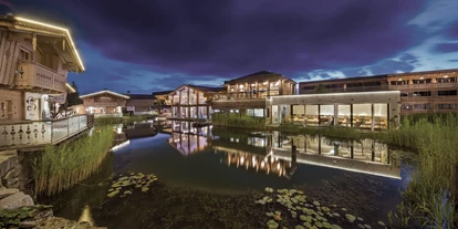 Wellnessurlaub - Private Spa - Otterbach (Sankt Florian am Inn) - INNs HOLZ Chaletdorf samt Blick auf den Wellnessbreich mit Indoorpool bei Nacht - INNs HOLZ Chaletdorf